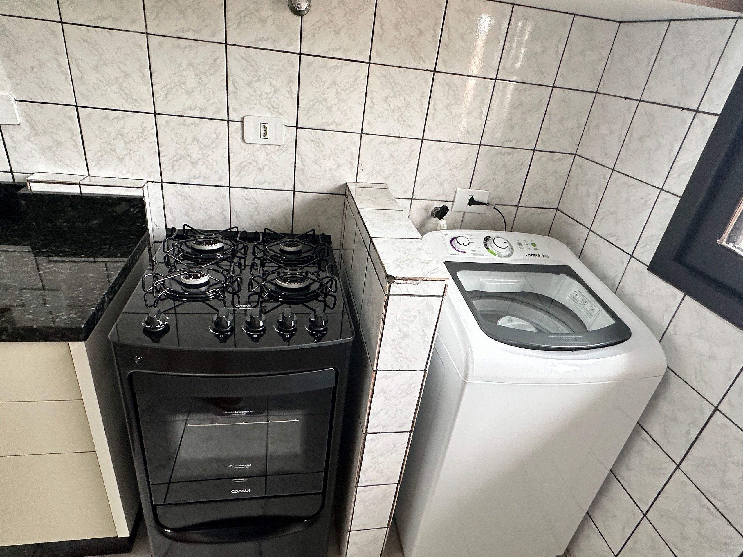 A kitchen with a gas stove and a front-loading washing machine.