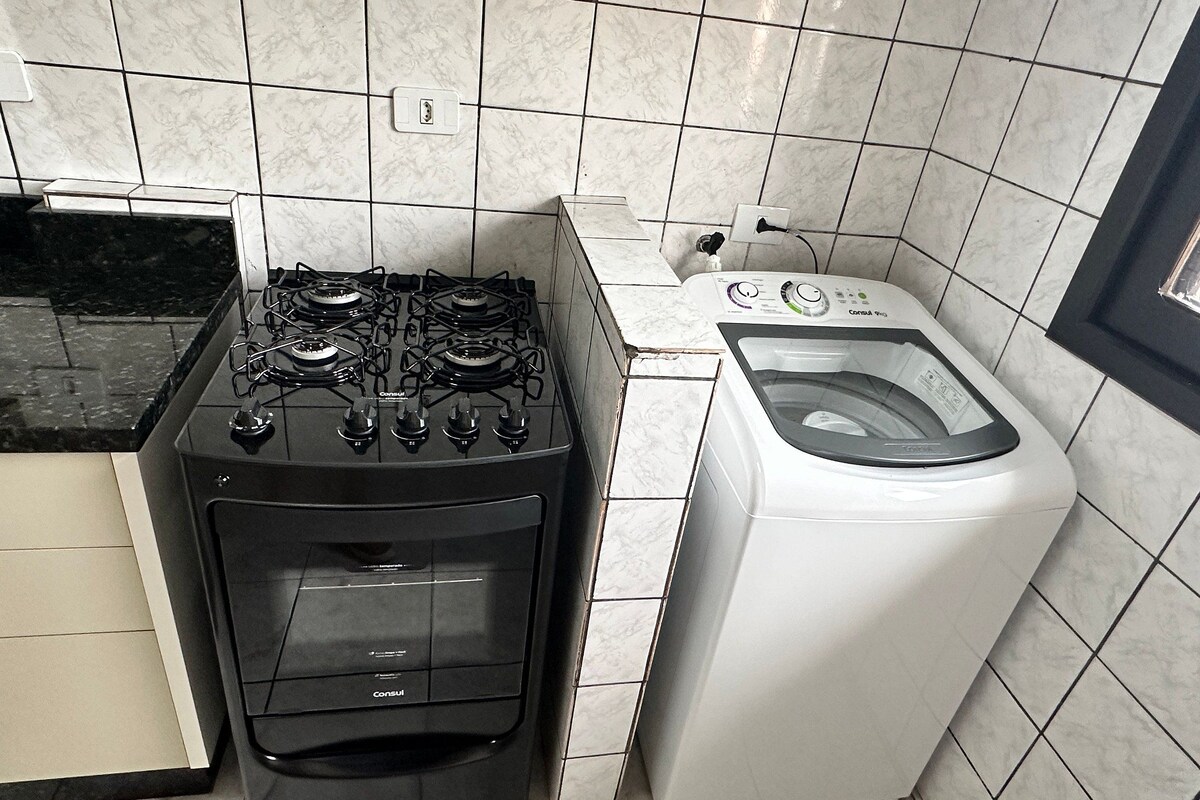Una cocina con estufa a gas y lavadora de carga frontal.