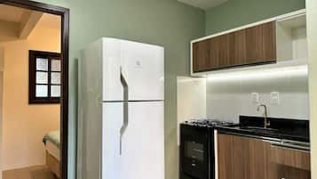 A compact kitchen with a white refrigerator, a stove, and wooden cabinets.