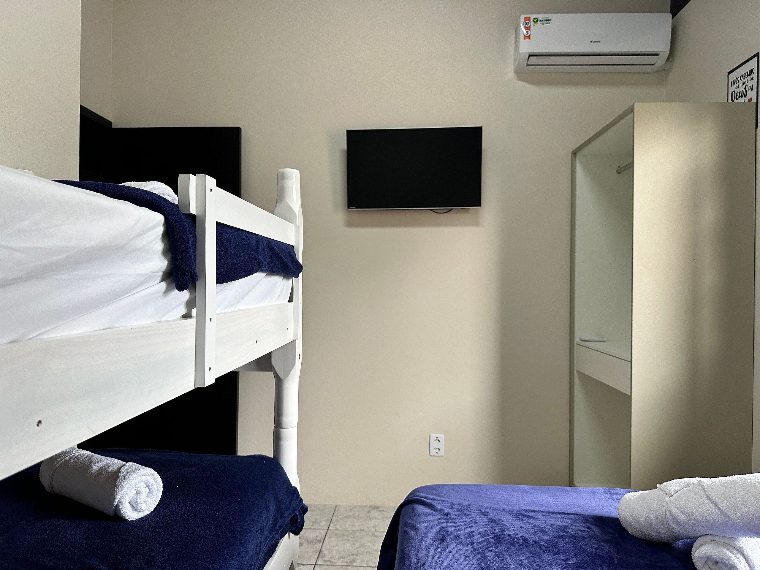 A room with two bunk beds, a flat-screen TV, an air conditioning unit, and a door.
