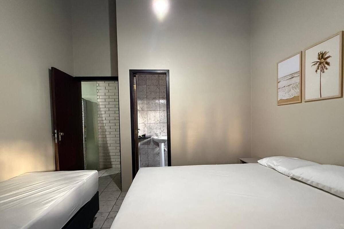 Ein Schlafzimmer mit zwei Betten, ein Badezimmer mit Fliesen und eine Tür zu einem anderen Raum.