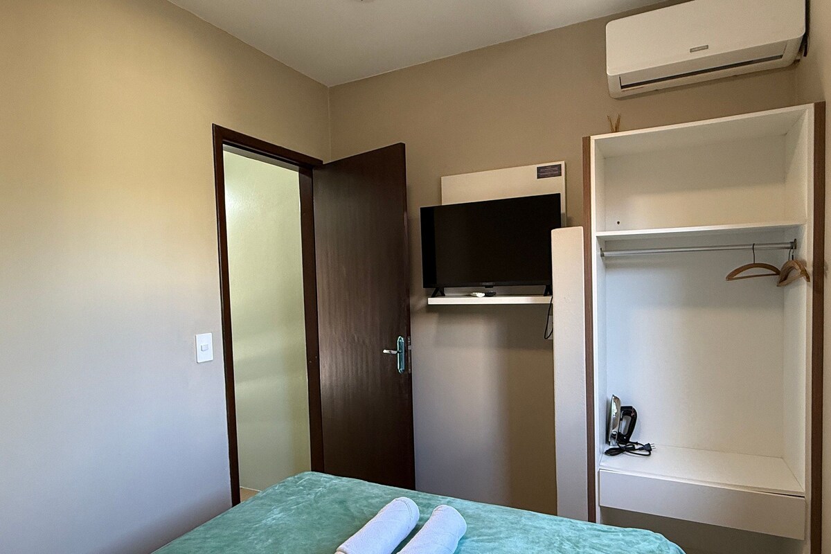 Habitación de hotel con cama, televisor montado en la pared, armario y aire acondicionado.
