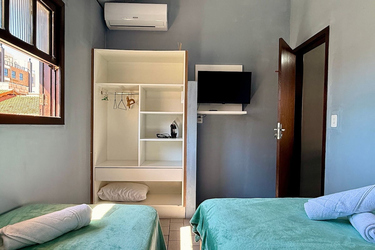 Ein Schlafzimmer mit zwei Betten, einem Kleiderschrank, einem Fernseher und einer Klimaanlage.