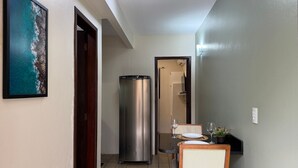 A hallway with a dining area, a refrigerator, and a framed picture of a coastal scene. - Ancoragem (Bombinhas)