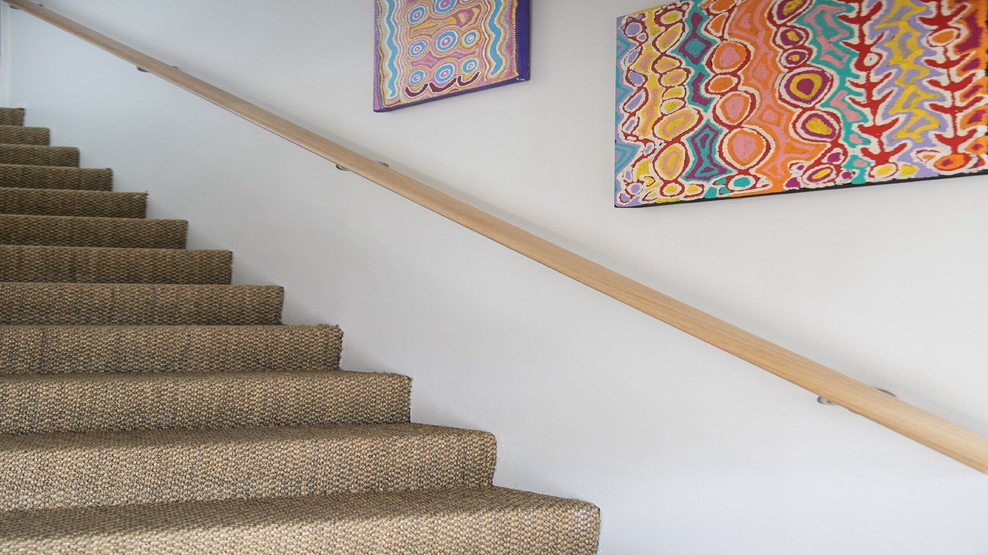 A staircase with carpeted steps and a wooden handrail.