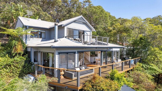A two-story house with a balcony, surrounded by dense greenery. - Bush setting and easy walk to beach (KILLCARE)