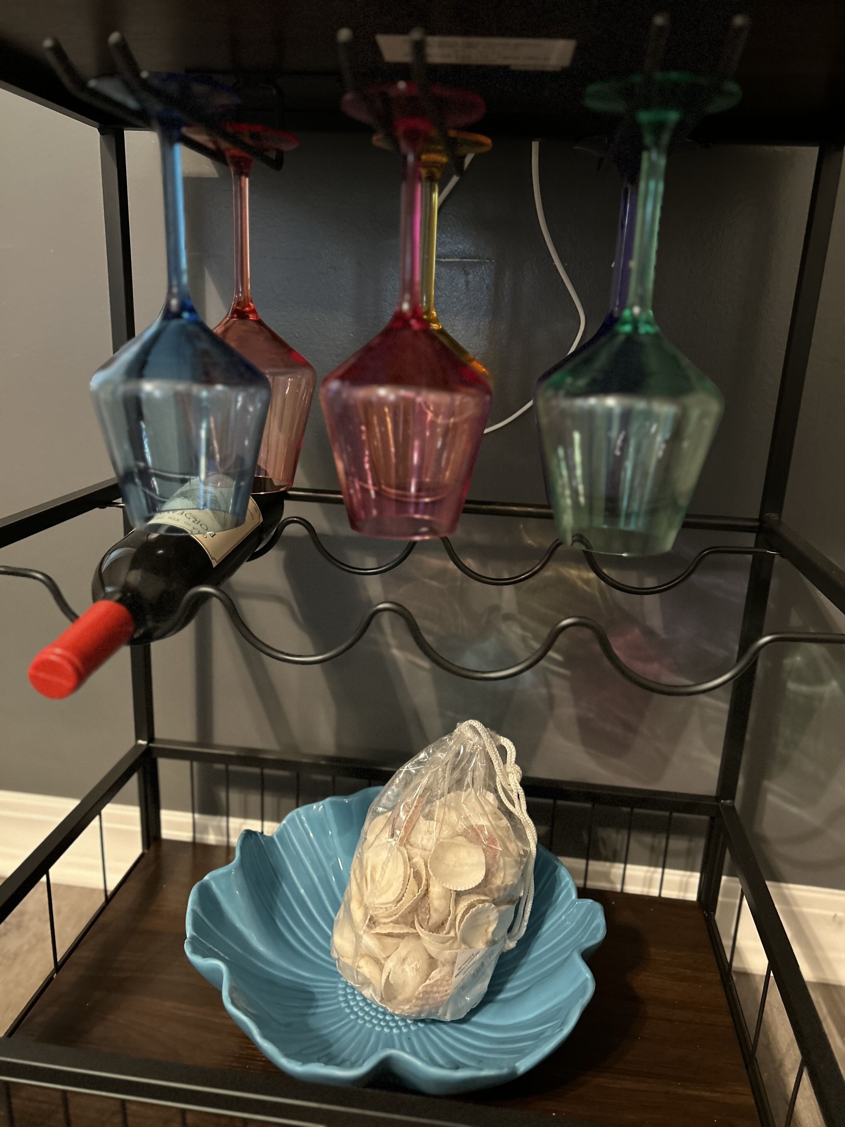 A shelf with various glass bottles and a plastic bag of snacks.