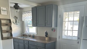 Una cocina con armarios grises, una estufa blanca y una ventana con vistas al exterior.