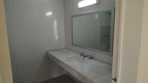 A small, clean bathroom with a single sink and mirror, tiled walls, and a light fixture above the mirror. - RESIDENCIA CASA BLANCA (Querétaro)