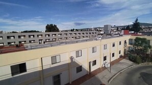 A multi-story building with a flat roof, several windows, and a parking area with a car. - RESIDENCIA CASA BLANCA (Querétaro)