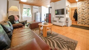 A cozy living room with a leather sofa, a wooden coffee table, and a television. - Ferienhaus in ruhiger Lage (Friedberg)