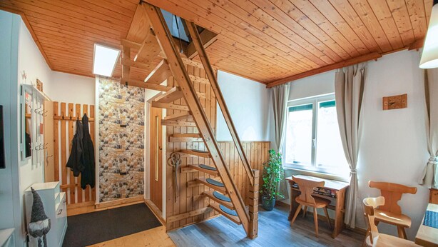 A wooden interior with a spiral staircase, stone wall, and a desk with chairs. - Ferienhaus in ruhiger Lage (Friedberg)