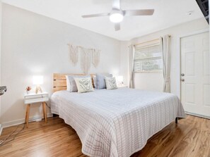 Ein Schlafzimmer mit Bett, Nachttisch, Wanddekoration und Deckenventilator.