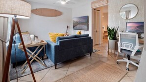 Una sala de estar moderna con sofá, escritorio, silla, lámpara y un cuadro.
