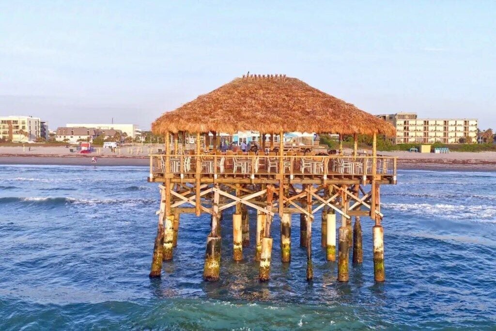 Un muelle de madera con una estructura de techo de paja, sostenida por múltiples pilares, que se adentra en el agua.