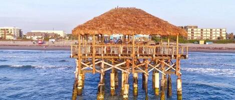 Un muelle de madera con una estructura de techo de paja, sostenida por múltiples pilares, que se adentra en el agua.