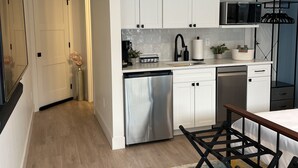 Une cuisine moderne avec des armoires blanches, des appareils en acier inoxydable et un plancher en bois.