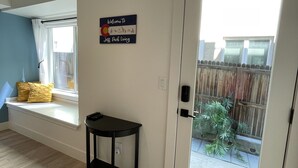 Une pièce dotée d’un banc près de la fenêtre, d’une porte donnant sur un balcon et d’une pancarte de bienvenue.