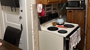 A kitchen with wooden cabinets, a white stove, a microwave, and a television mounted on the wall. - Historical section of Chesapeake. Propertie nice and groomed quiet neighborhood. (Chesapeake)