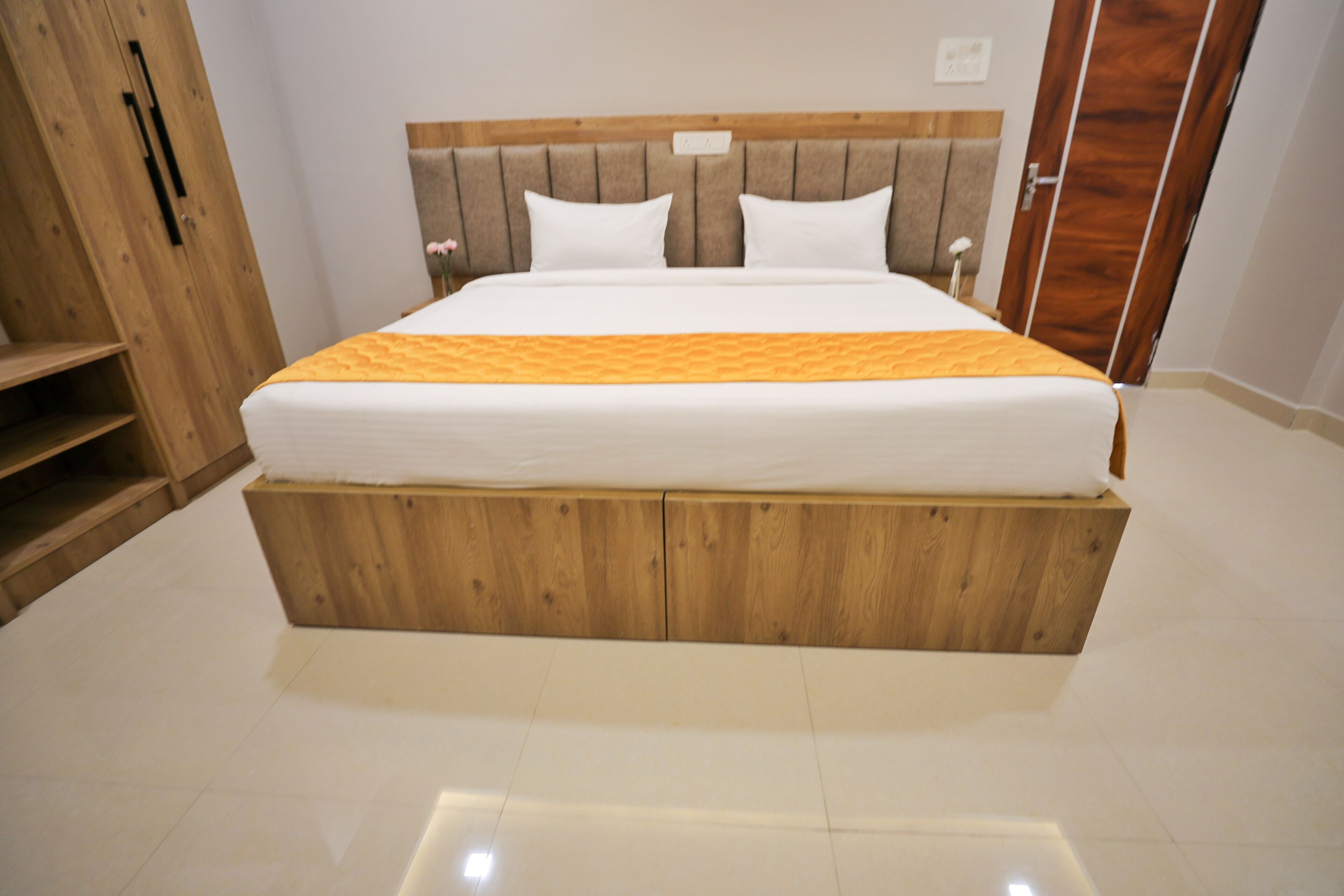 Un dormitorio con cabecera de madera, cama con ropa de cama blanca y un armario de madera.