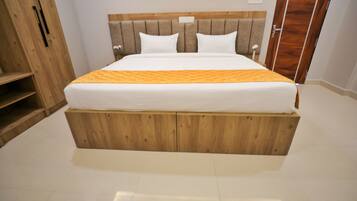 Un dormitorio con cabecera de madera, cama con ropa de cama blanca y un armario de madera.