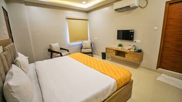 A bedroom with a bed, a chair, a TV, and a wooden cabinet.