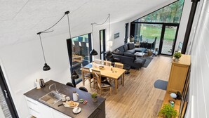 A modern kitchen with a dining area, a living room with a sofa, and large windows offering a view of the outdoors. - "Skakke" - 900m from the sea by Interhome (Hals)