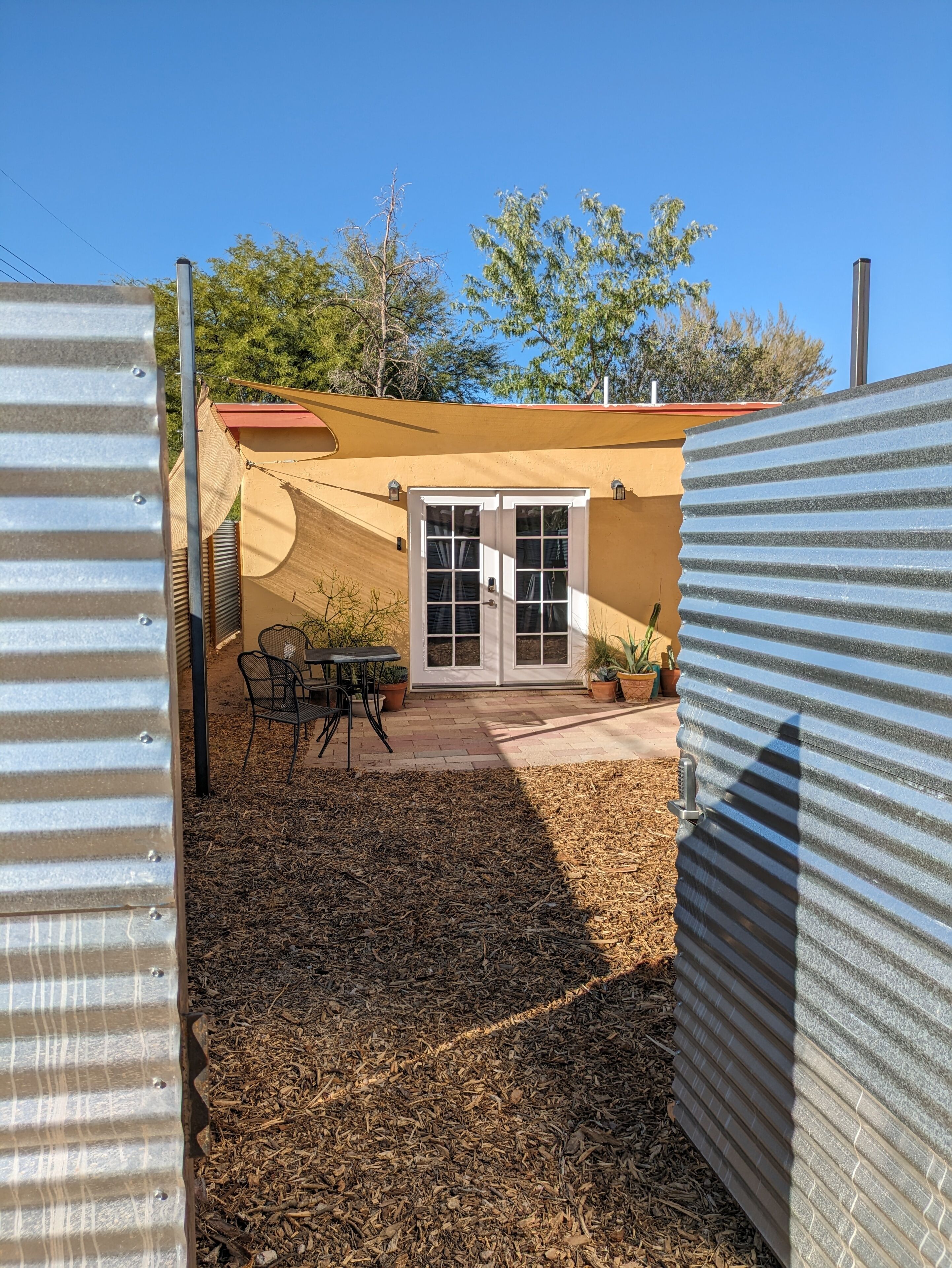 Un patio con una mesa, sillas, una puerta y plantas en macetas.