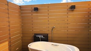 A modern bathroom with a freestanding bathtub, wooden panel walls, and a visible showerhead.