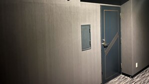 A hallway with a door marked 306, a small rectangular panel, and a textured floor.