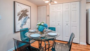 A dining area with a glass table, blue chairs, and a framed artwork on the wall. - Welcome to Your Vacation Home (Clearwater)