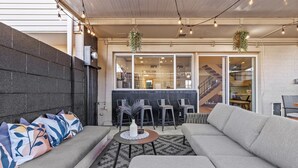 Un espacio moderno con sala, sofá, una pequeña mesa redonda y una zona de bar con sillas.