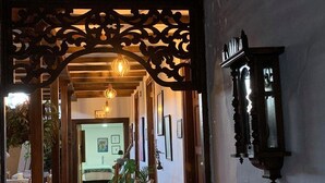 A hallway with a wooden archway, a bed in the background, and a wall-mounted light fixture. - La Estancia Hotel Boutique  (Salamina)