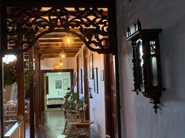 Un pasillo con un arco de madera, una cama al fondo y una lámpara fijada a la pared.