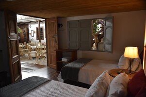 Una habitación acogedora con dos camas, techo de madera y una pequeña mesa con lámpara.