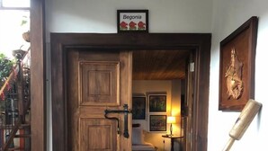 A wooden door leading to a bedroom with a bed, a nightstand, and a lamp. There is a wooden ladder and a shelf with books and a green bag. - La Estancia Hotel Boutique  (Salamina)