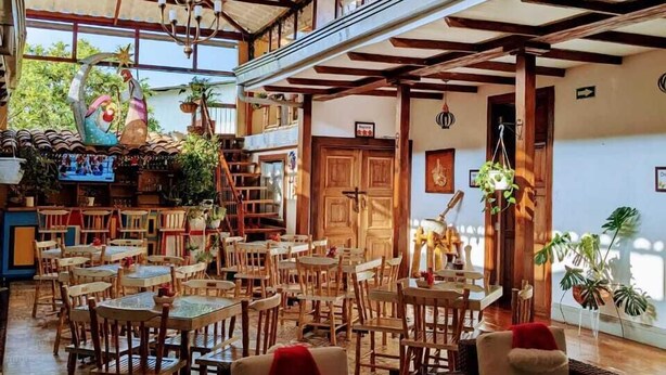 A spacious indoor area with wooden tables and chairs, a staircase, and a variety of potted plants. - La Estancia Hotel Boutique  (Salamina)
