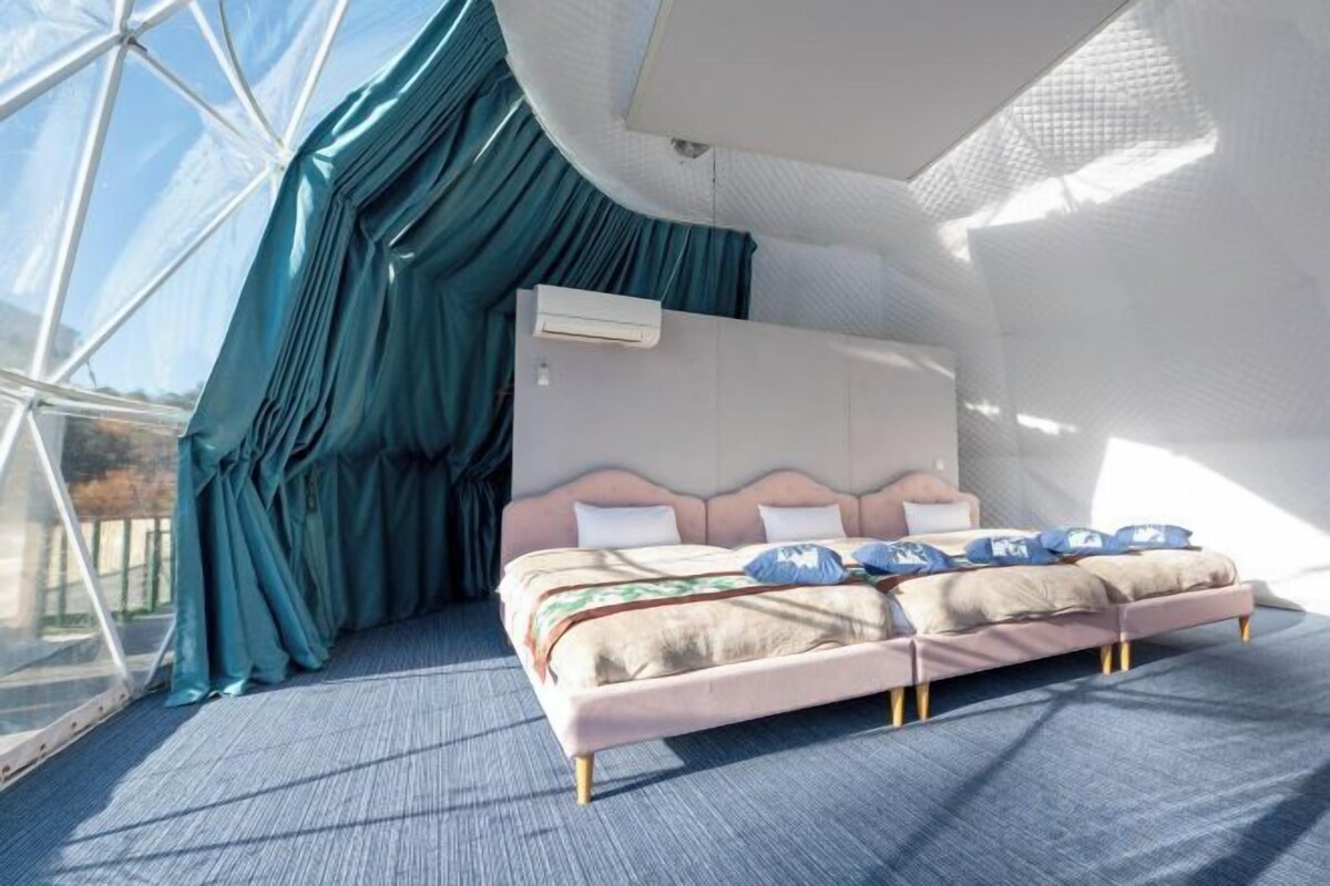 A bedroom with a bed, curtains, and an air conditioning unit.