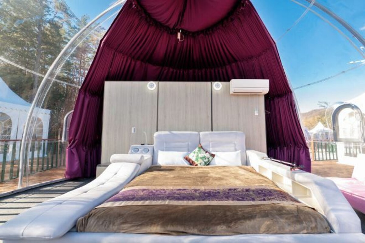 A tent-style bedroom with a bed, pillows, and a blanket.