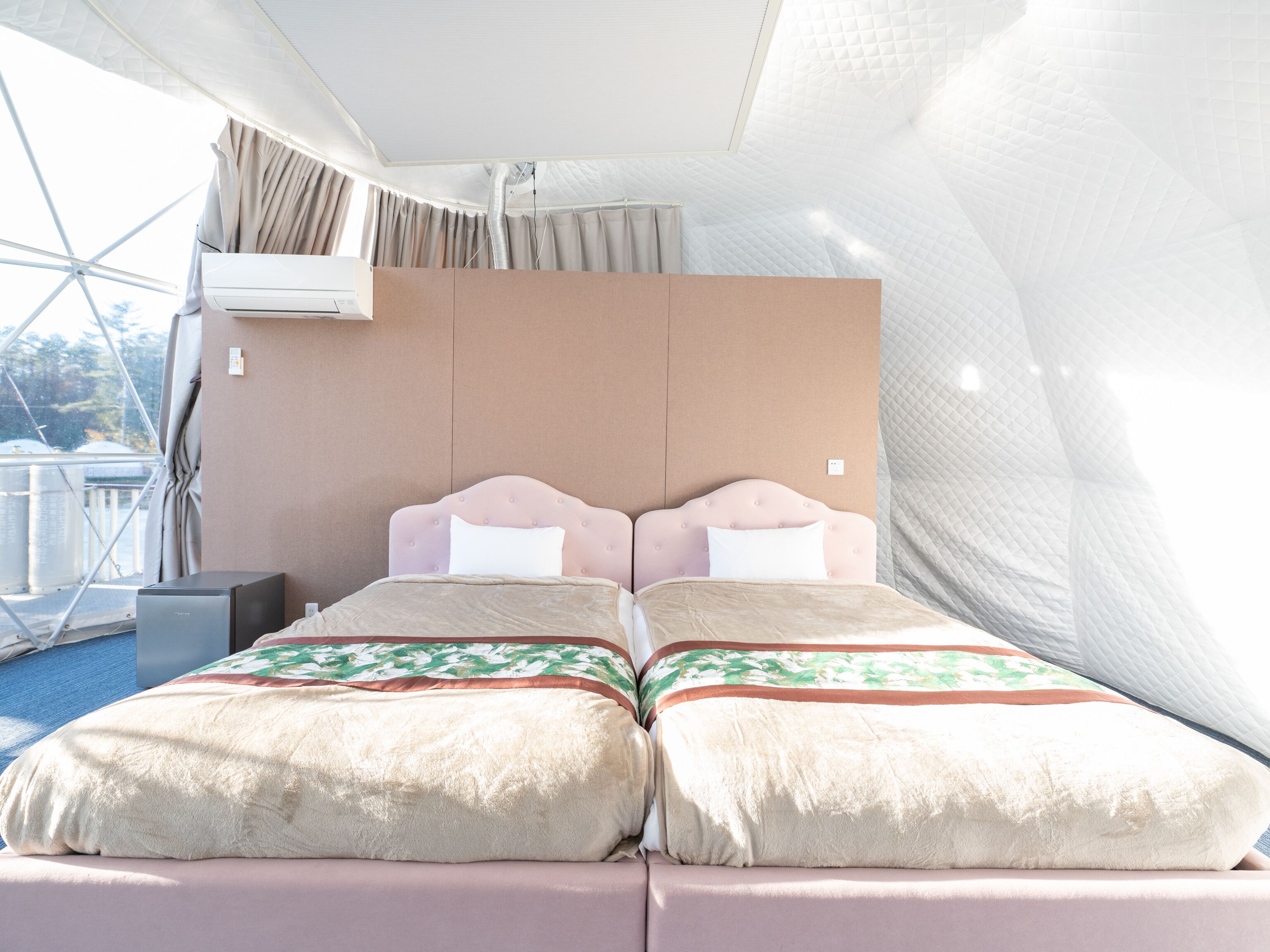 A double bed with a headboard, a bedside table, and an air conditioning unit.