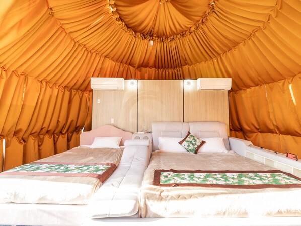 A tent-style room with two beds, each with a pillow and a blanket. There are two air conditioning units on the wall. - Fuji Hoshizorano Mura Tabist (Narusawa)