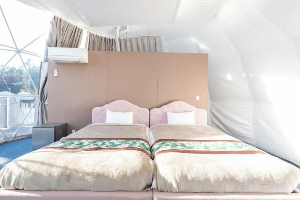 A bedroom with two beds, a window, and an air conditioning unit.