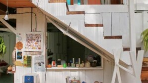 A small, rustic kitchen with a wooden table, a water dispenser, and various kitchen items. - CASA BOHÖ (Cahuita)