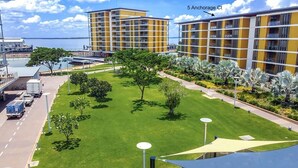 A hotel with a central lawn, multiple balconies, and a view of the sea. - Waterfront Sunset Suite: 1 Bed Apt, Sunset Views (Darwin City)