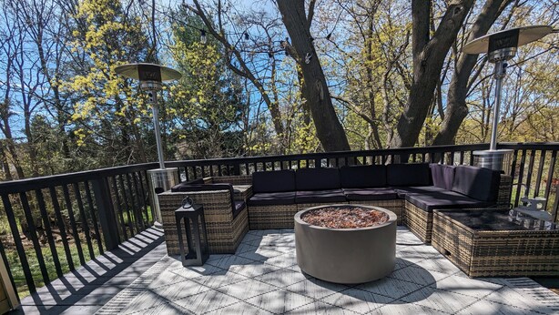 A deck with wicker furniture, a fire pit, and string lights.