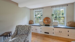 A room with a patterned sofa, a wooden table, a window seat with plants, and a decorative globe.