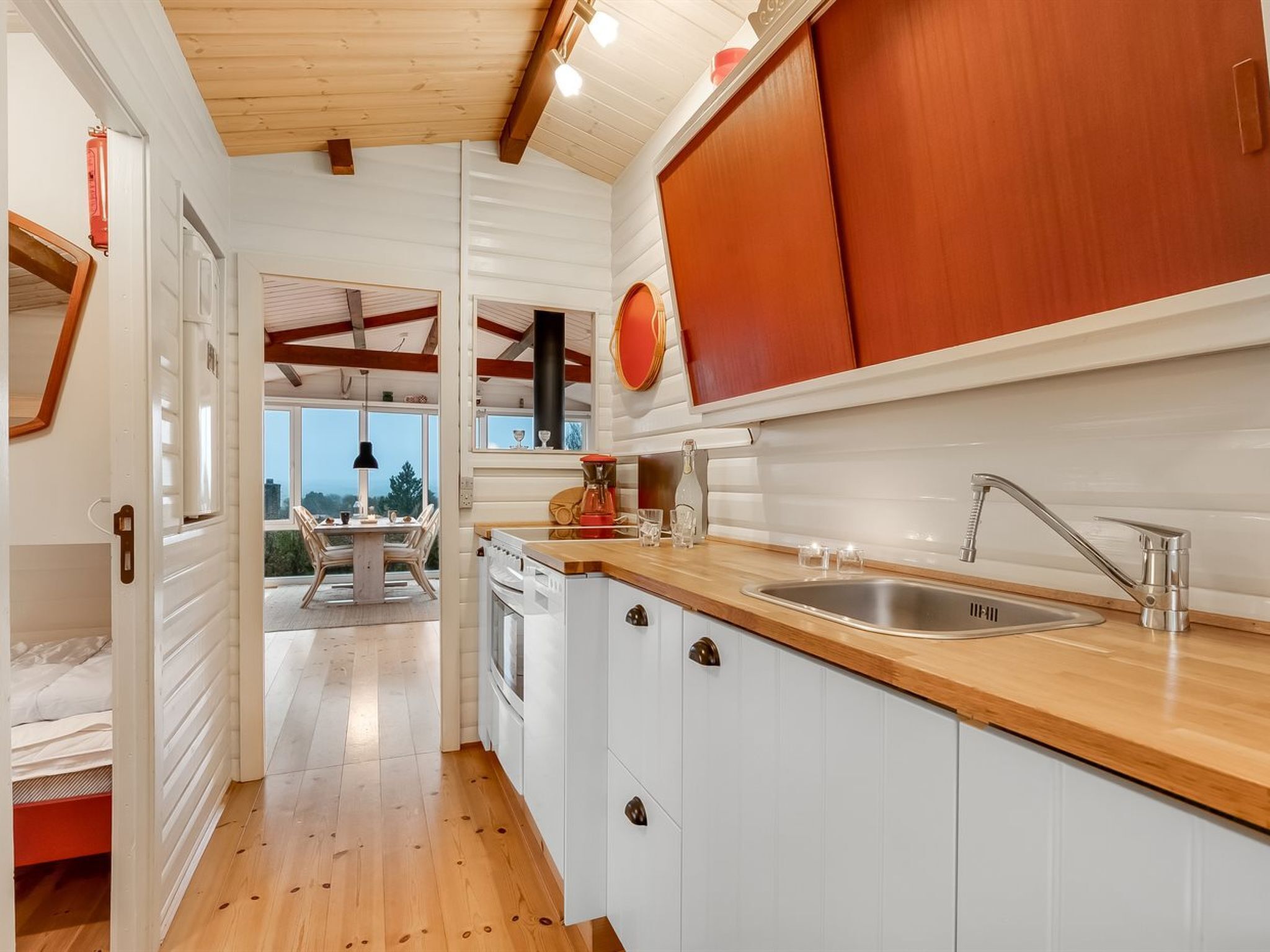 Une cuisine moderne avec des armoires blanches, des comptoirs en bois et une grande fenêtre donnant sur un paysage magnifique.