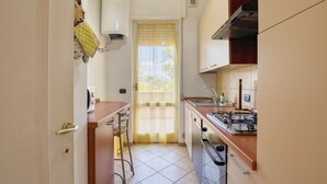 Eine kleine Küche mit Gaskochfeld, Spüle und einem Fenster mit gelbem Vorhang.