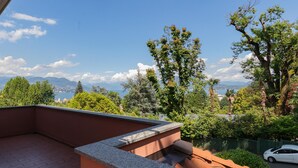 Ein Balkon mit Steg, der auf einen üppigen Garten und eine gebirgige Landschaft blickt.