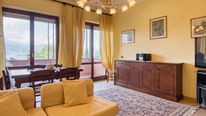 Ein Wohnzimmer mit einer Couch, einem Esstisch und Blick ins Freie.